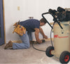 Ingersoll Rand P1.5IU-A9 Garage Mate 2 HP vertical air compressor beside a contractor using a pneumatic tool during flooring installation